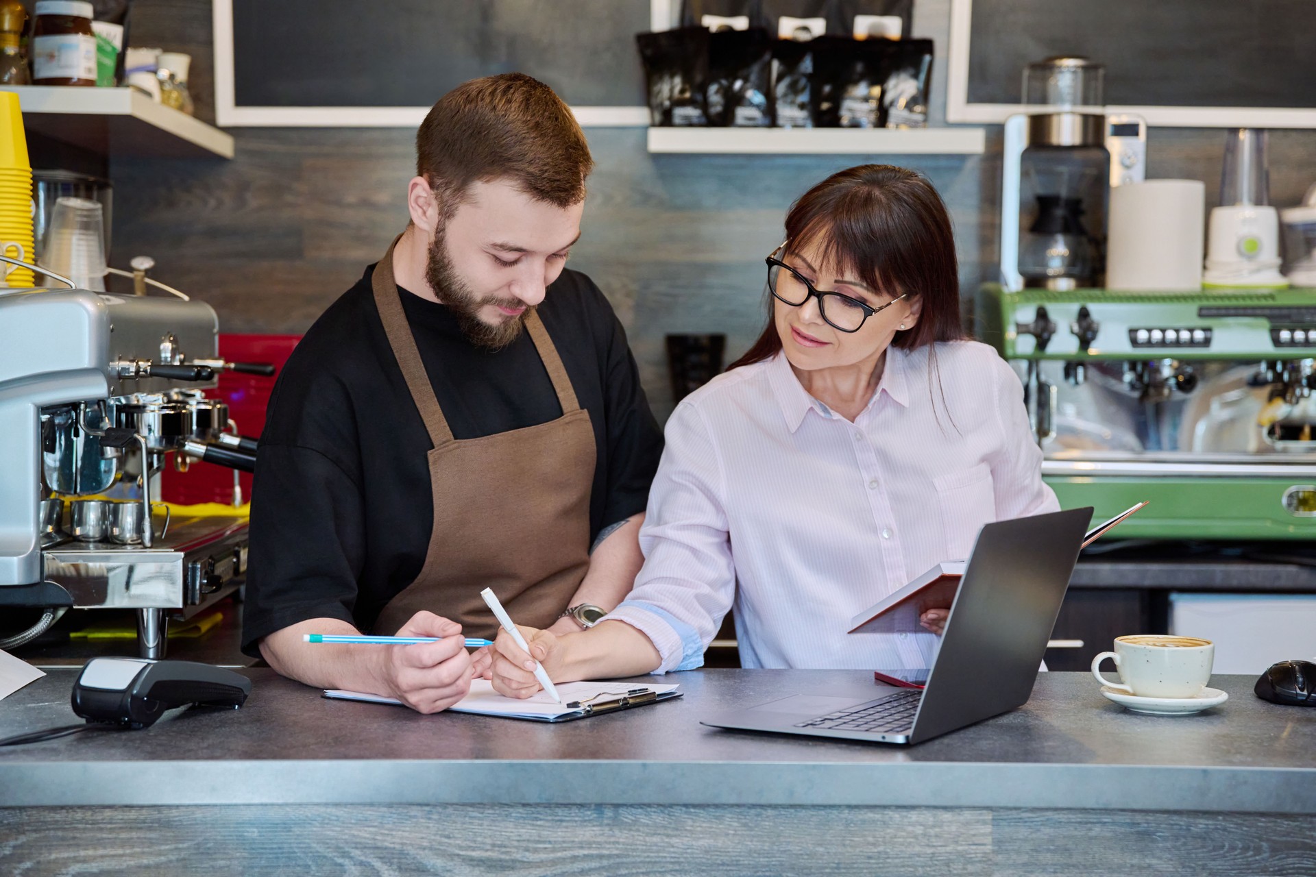 Team male and woman talking, working, using laptop, coffee shop